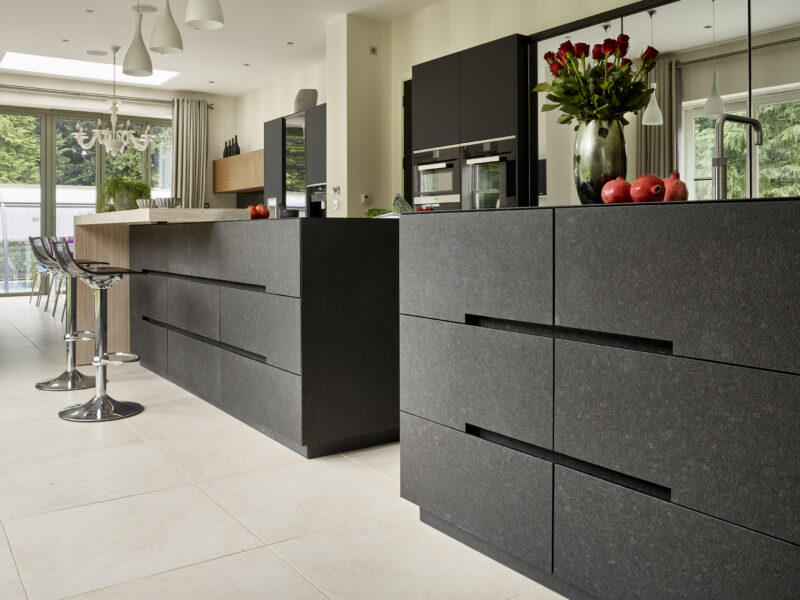 Large London kitchen with modern black details, mirrored cabinet and a wooden breakfast bench