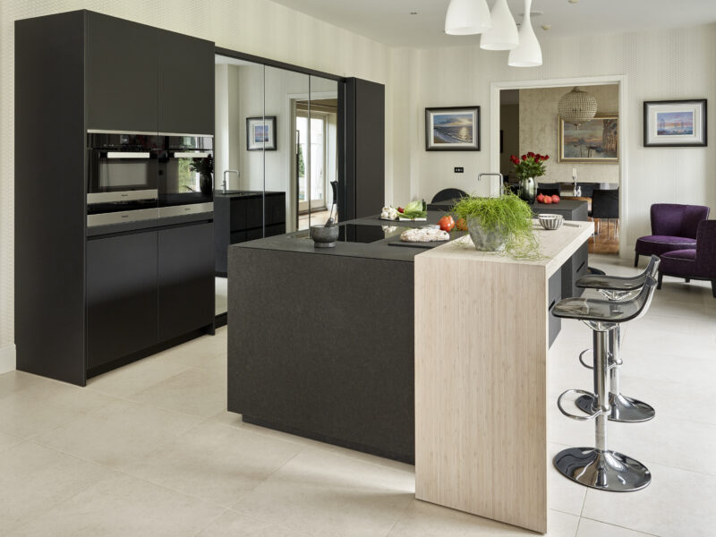Large London kitchen with modern black details, mirrored cabinet and a wooden breakfast bench