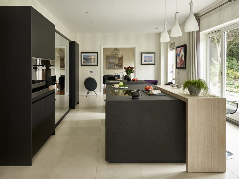 Large London kitchen with modern black details, mirrored cabinet and a wooden breakfast bench
