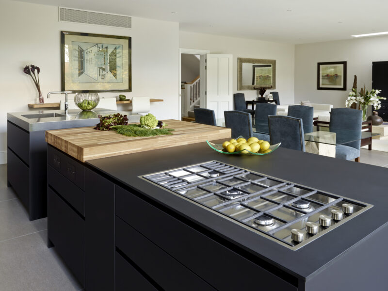 Open plan kitchen diner with blue cabinets, steel sink and wooden chopping board top with inbuilt gas hob