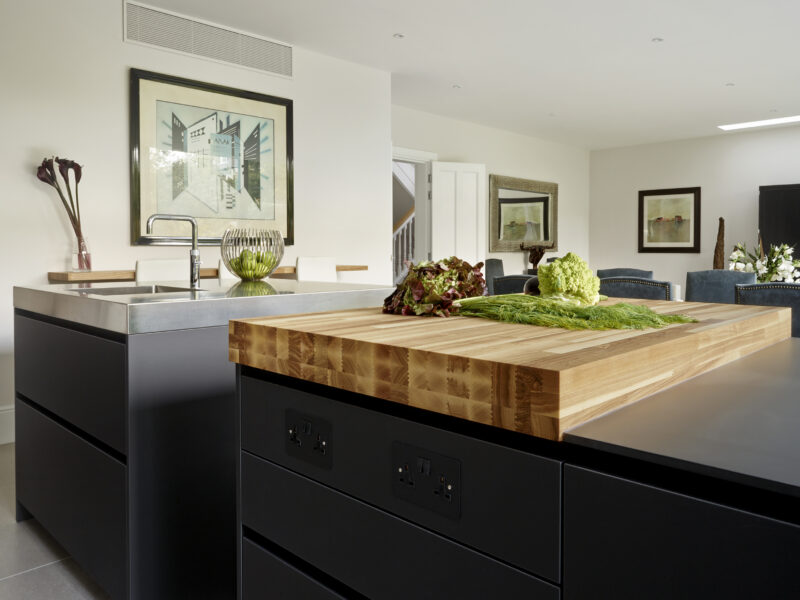 Open plan kitchen diner with blue cabinets, steel sink and wooden chopping board top