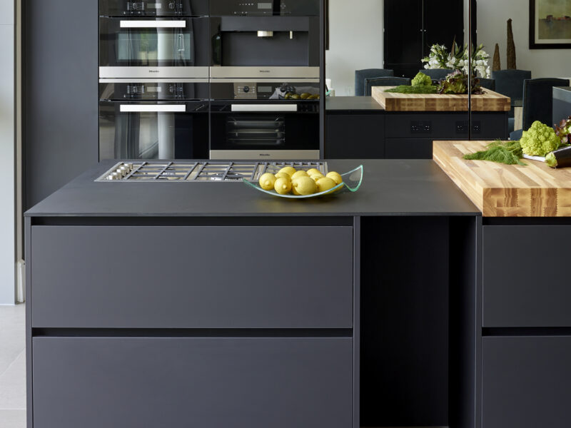Open plan kitchen diner with blue cabinets, steel sink and wooden chopping board top with inbuilt gas hob