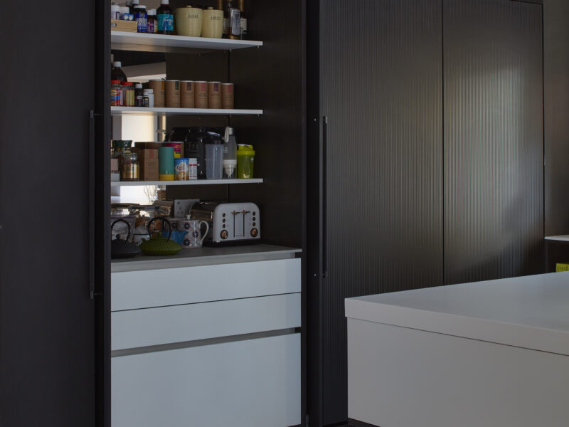 Modern, black and white kitchen with drop lights and hidden storage and a wine fridge