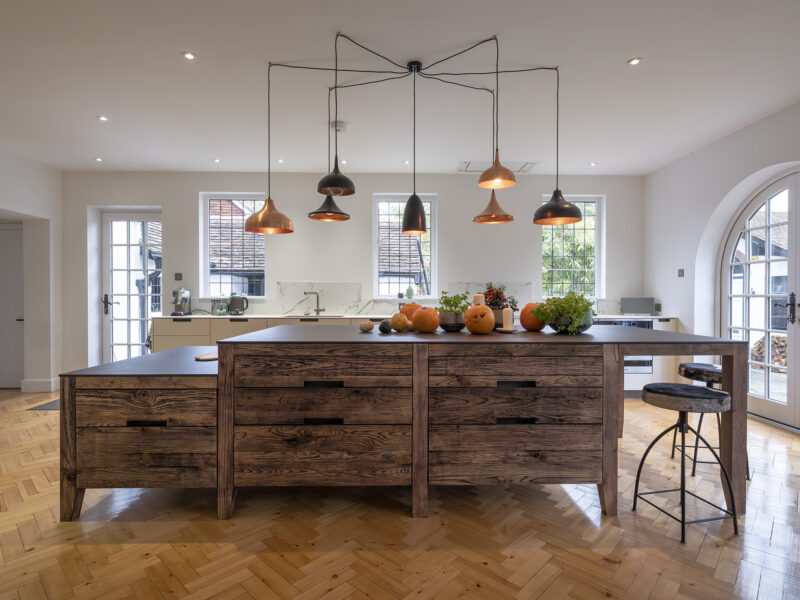 Large kitchen design with herringbone flooring and kitchen islands and floating log burner