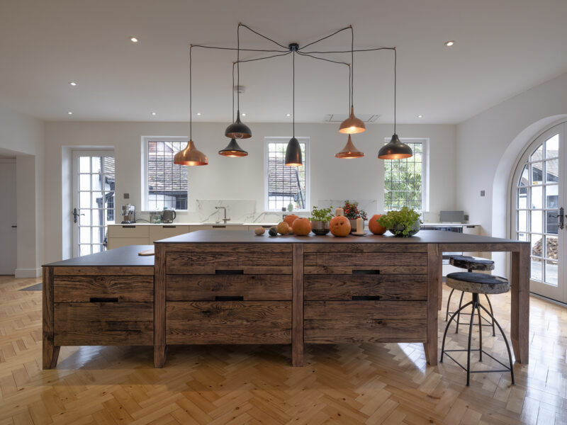 Large kitchen design with herringbone flooring and kitchen islands and floating log burner