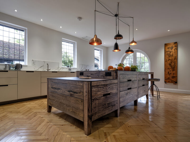 Large kitchen design with herringbone flooring and kitchen islands and floating log burner