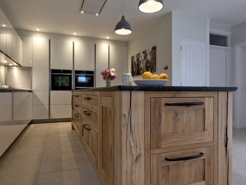 modern kitchen with floor to ceiling cabinets and marble looking island with gas hob - blue lights, white counter tops and a cow painting