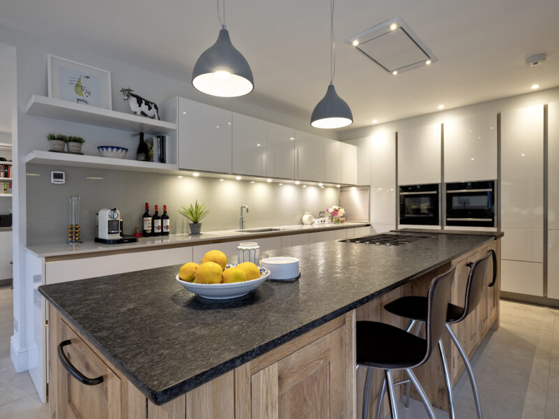 modern kitchen with floor to ceiling cabinets and marble looking island with gas hob - blue lights, white counter tops and a cow painting