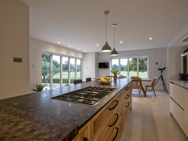 modern kitchen with floor to ceiling cabinets and marble looking island with gas hob - blue lights, white counter tops and a cow painting