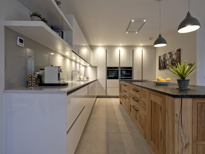 modern kitchen with floor to ceiling cabinets and marble looking island with gas hob - blue lights, white counter tops and a cow painting