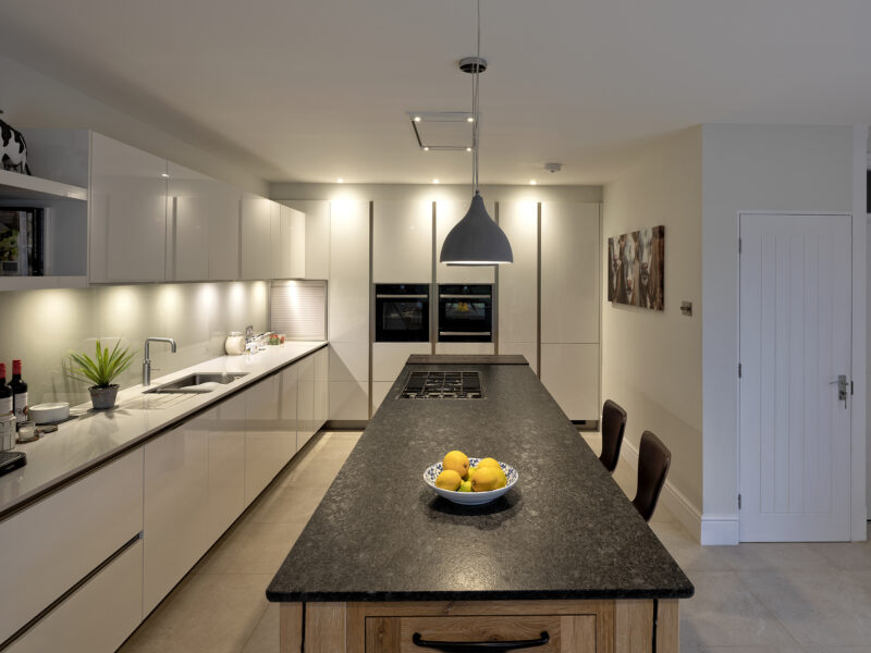 modern kitchen with floor to ceiling cabinets and marble looking island with gas hob - blue lights, white counter tops and a cow painting