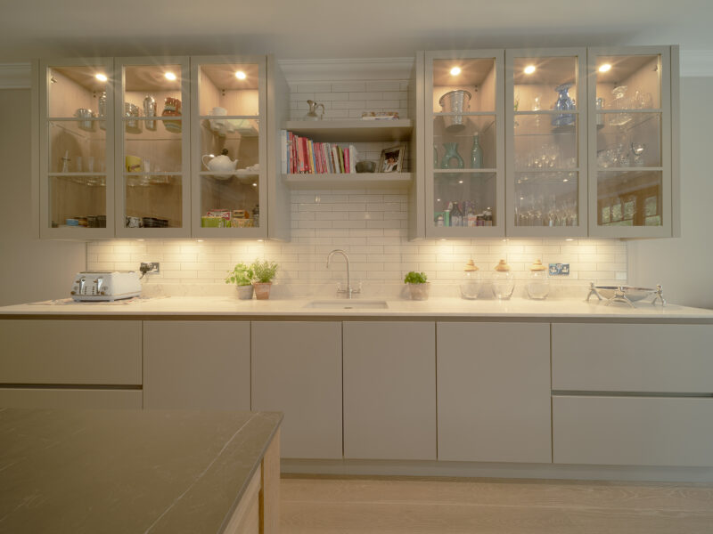 Modern kitchen, white cabinets, glass cabinets, decorative shelves over the sink with books on and subway white tiles