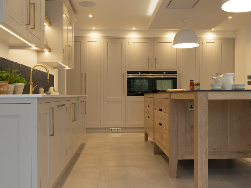 Kitchen hexagonal back splash with gold taps and shaker cupboards with timber island and drawers