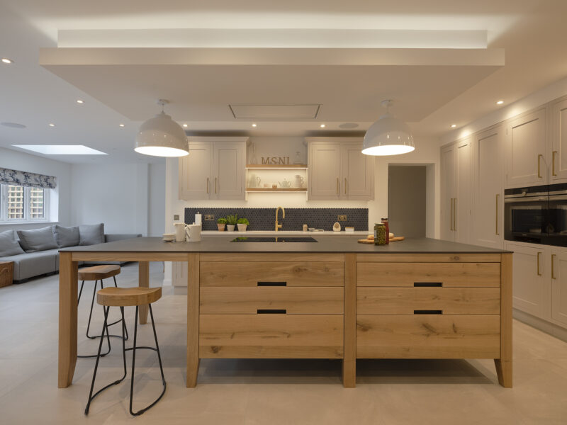 Kitchen hexagonal back splash with gold taps and shaker cupboards with timber island and drawers