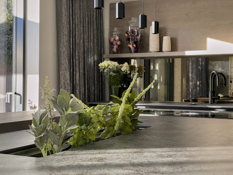 close up of modern grey kitchen, sink in background, plants on the island table